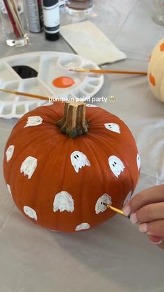 someone is painting a pumpkin with ghost faces on it