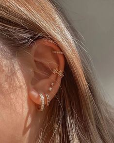 a woman wearing ear piercings with two small stars on the side of her ear