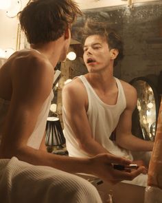 two young men sitting in front of a mirror