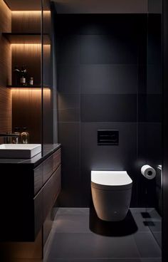 a modern bathroom with black walls and flooring is lit by recessed lighting above the toilet