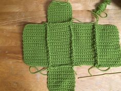 four green crocheted squares sitting on top of a wooden table