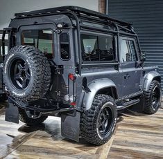 a black jeep is parked in front of a garage door and another vehicle behind it