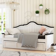 a white daybed with pillows and blankets on it