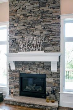 a living room with a stone fireplace and two windows