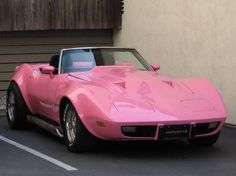 a pink car parked in front of a building