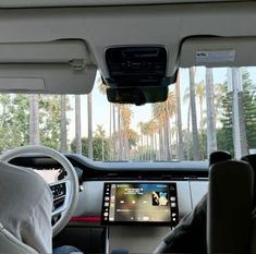 the interior of a car with palm trees in the background and an electronic display on the dashboard