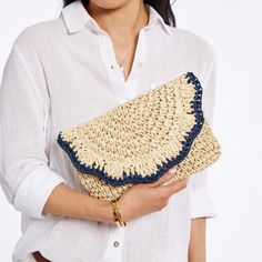 a woman wearing a white shirt holding a straw bag with blue trimmings on it