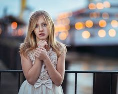 a beautiful young blonde woman standing next to a railing