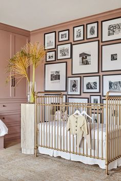 a baby's crib with pictures on the wall and a vase full of flowers