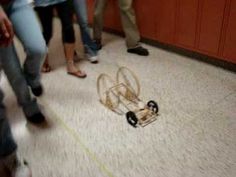 a group of people standing next to each other near a toy car on the floor