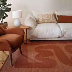 a living room with a couch, chair and lamp on the side table in front of it