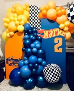 some balloons are in the shape of cars and checkered flags on a race car backdrop