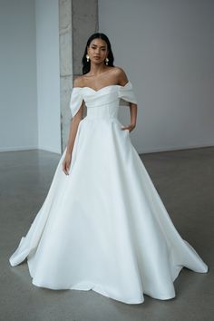 a woman in a white wedding dress posing for the camera with her hands on her hips