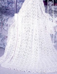 a woman in a white crochet dress is sitting on a bed with her back to the camera