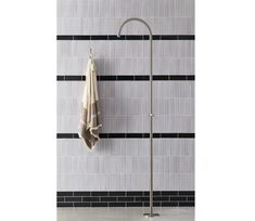 a towel is hanging on a pole in front of a tiled wall with black and white tiles