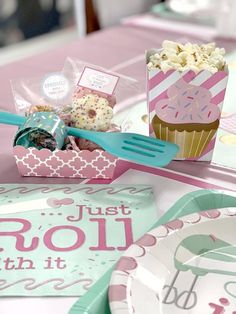 a pink and white table with cupcakes, paper plates and utensils