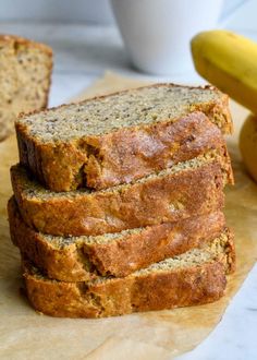 slices of banana bread stacked on top of each other next to some bananas and a cup