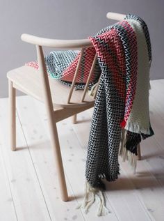 a chair with a blanket on top of it and a wooden arm rest next to it