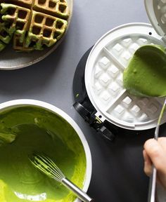 two waffles with green liquid in them being stirred by a whisk