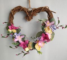 a heart shaped wreath with flowers hanging on the wall