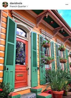 an orange house with green shutters and potted plants