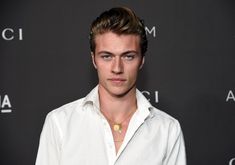 a young man wearing a white shirt and gold necklace