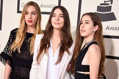 three women standing next to each other on a red carpet