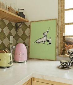 a kitchen counter with toaster, kettle and pictures on the wall