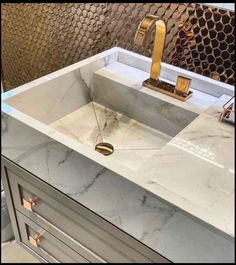 a bathroom sink with a gold faucet and marble counter top in the middle