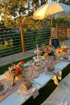 an outdoor table set up with plates and desserts