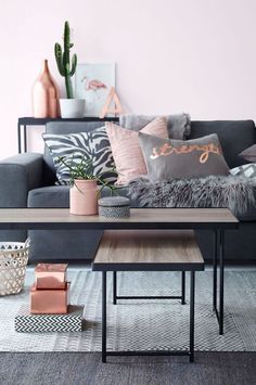 a living room with grey couches and pillows on top of the rugs in front of them