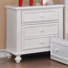 a white dresser with two drawers and red shoes on top