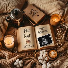 an open book sitting on top of a bed next to candles