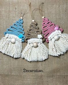 three small christmas ornaments with tassels and bells hanging from the side on a piece of fabric