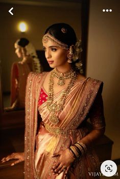 a woman in a bridal outfit with jewelry on her neck and hands behind her back