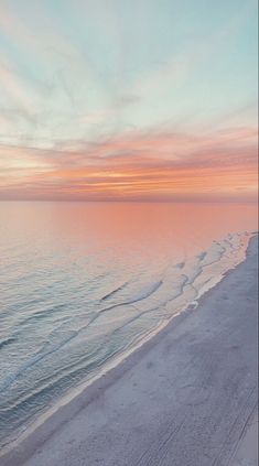 the beach is covered in white sand as the sun sets