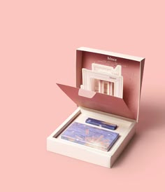 an open box with a piece of paper inside it on a pink background that has the image of a building in it