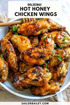 a white bowl filled with chicken wings and garnished with parsley