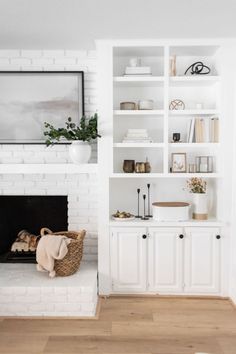 a living room with white bookcases and a fireplace