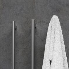 a white towel hanging on the side of a wall next to two metal pole holders