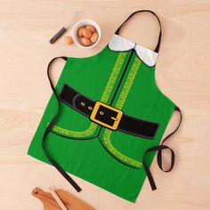 a green apron with a black belt on it and eggs in a bowl next to it