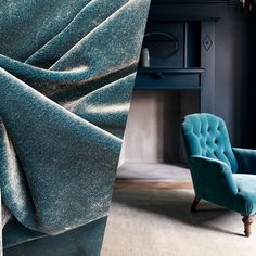 a blue chair sitting in front of a fireplace next to a wall with a mirror on it