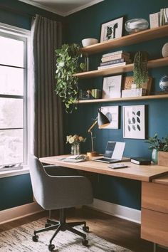 a desk with a laptop on it in front of a window and bookshelves