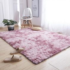 a living room with a pink rug on the floor next to a chair and potted plant