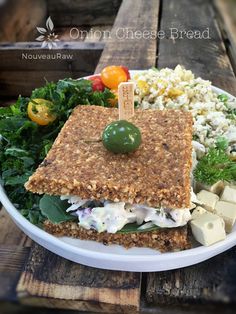 a white plate topped with food on top of a wooden table next to a bowl of salad