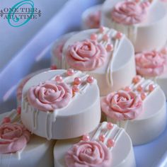 some white and pink decorated cookies on a blue platter with flowers in the middle