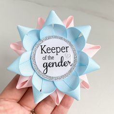 a hand holding a blue and pink flower with the words keeper of the gender on it