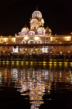 a large building lit up at night with lights reflecting in the water