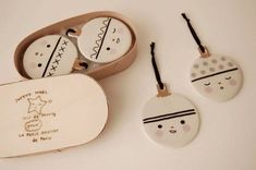 three ceramic ornaments in a box on a white surface with black and white designs, including one for children's head