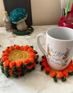 there is a coffee cup on the table next to some crocheted coasters